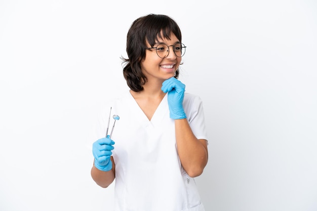 Jeune femme tenant des outils isolés sur fond blanc regardant sur le côté et souriant