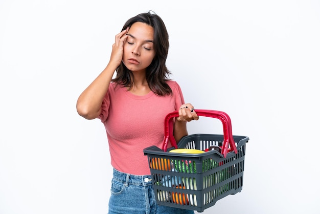 Jeune femme tenant un panier rempli de nourriture avec des maux de tête