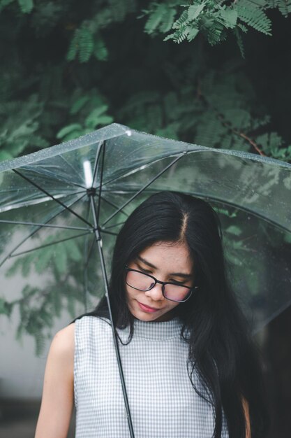 Photo une jeune femme tenant un parapluie debout contre des arbres