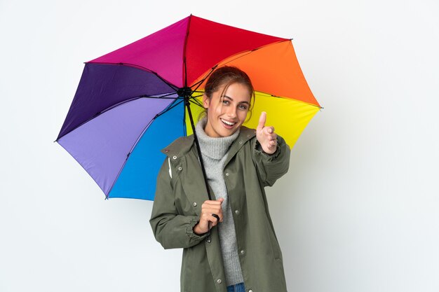 Jeune femme tenant un parapluie isolé sur un mur blanc se serrant la main pour conclure une bonne affaire