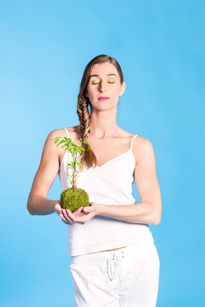 Jeune femme tenant un petit arbre