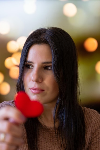 Jeune femme tenant un petit coeur rouge