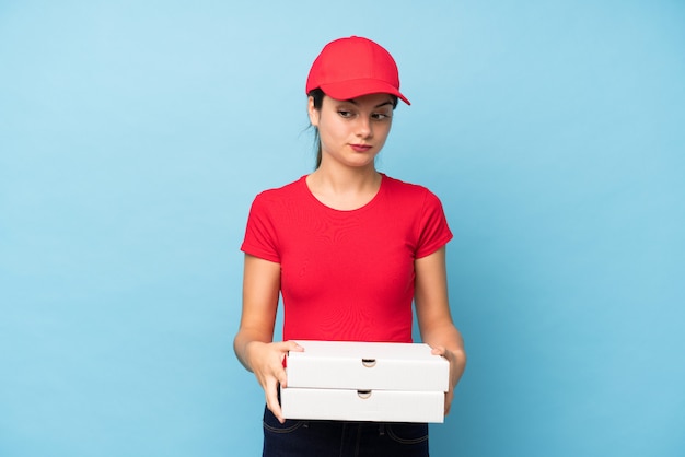 Jeune femme tenant une pizza sur un mur rose isolé, pensant à une idée