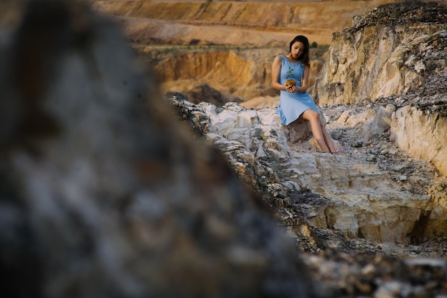 Photo une jeune femme tenant une plante assise sur un rocher