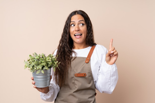 Jeune femme tenant une plante dans l’intention de réaliser la solution tout en levant le doigt