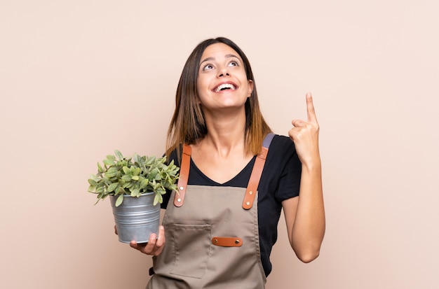 Jeune femme tenant une plante dans l’intention de réaliser la solution tout en levant le doigt