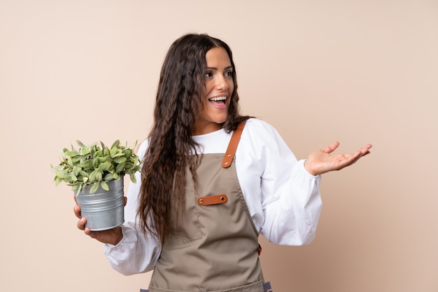 Jeune femme tenant une plante avec une expression faciale surprise