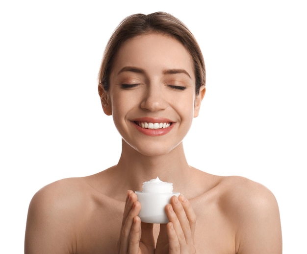 Jeune femme tenant un pot de crème pour le visage sur fond blanc