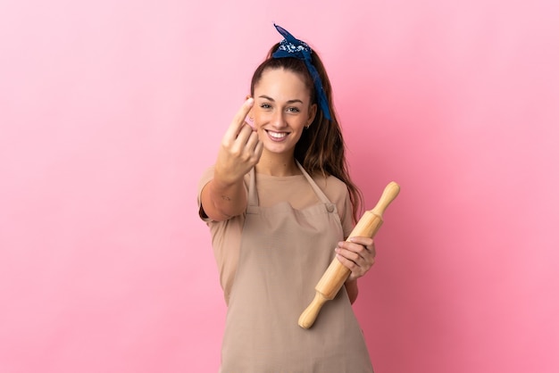 Jeune femme tenant un rouleau à pâtisserie faisant un geste à venir