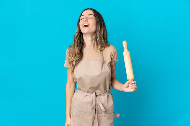 Jeune femme tenant un rouleau à pâtisserie posant isolé contre le mur blanc