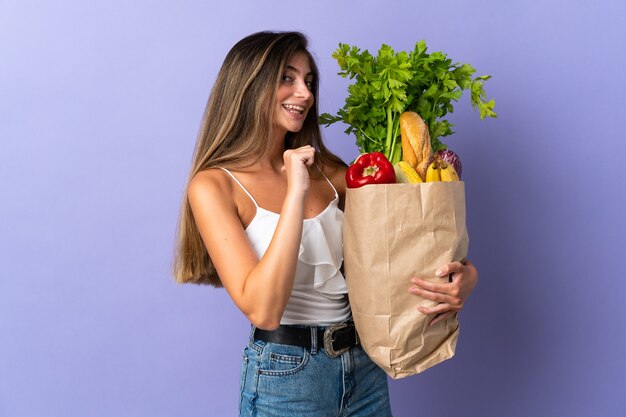 Jeune femme tenant un sac d'épicerie fier et satisfait de soi