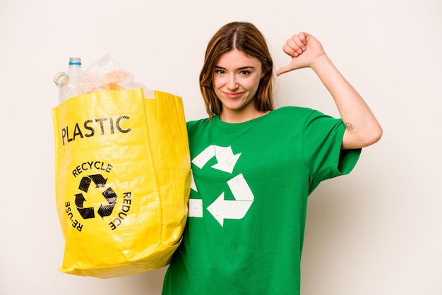 Jeune femme tenant un sac plein de bouteilles en plastique à recycler isolé sur fond blanc se sent fier et confiant exemple à suivre