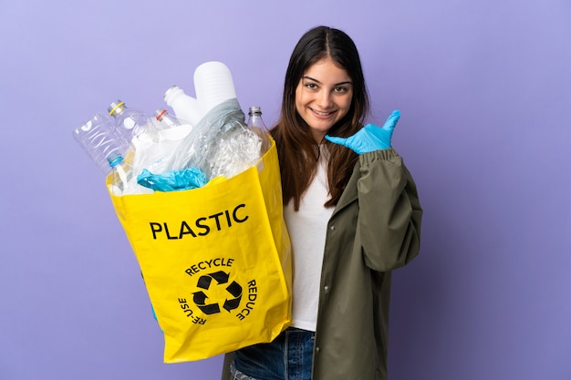 Jeune femme tenant un sac plein de bouteilles en plastique à recycler