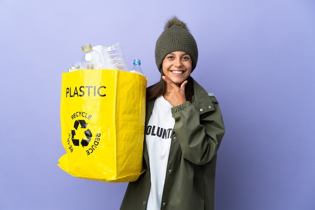 Jeune femme tenant un sac plein de plastique heureux et souriant