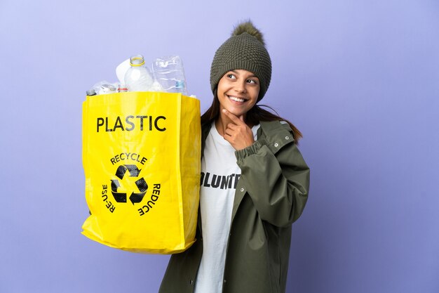 Jeune femme tenant un sac plein de plastique à la recherche en souriant