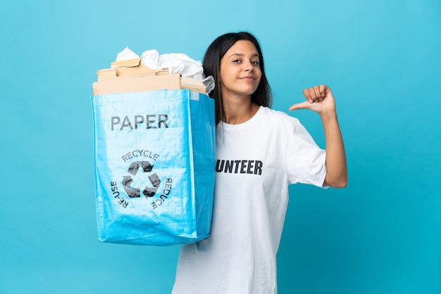 Jeune femme tenant un sac de recyclage plein de papier fier et satisfait de soi