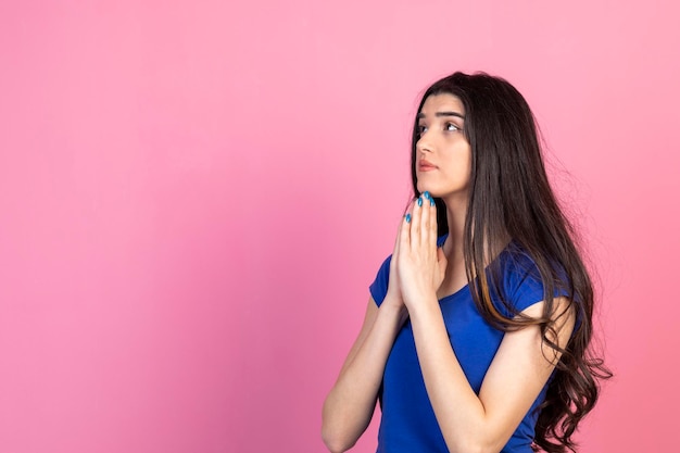 Jeune femme tenant ses mains ensemble et priant