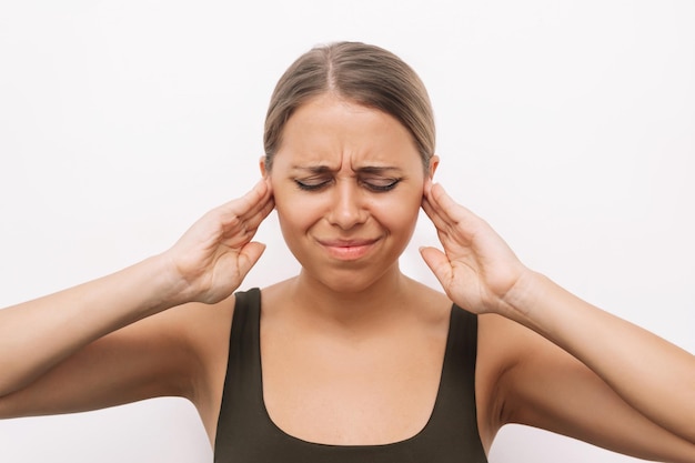 Jeune femme tenant ses oreilles avec ses mains Douleur et acouphènes Otite de l'oreille Refus d'entendre