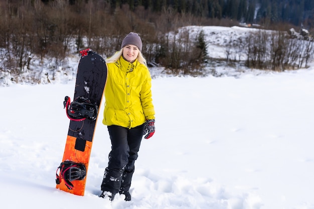 Jeune femme tenant un snowboard à la station d'hiver