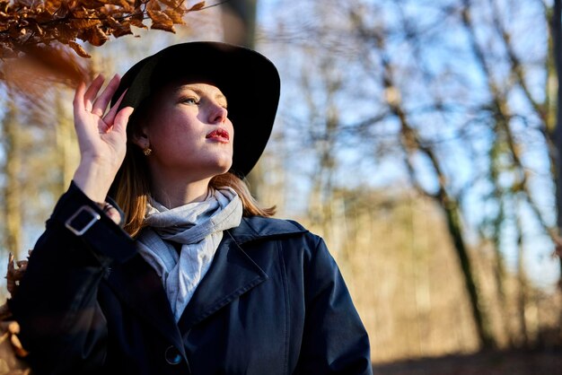 Jeune femme tenant son chapeau en forêt