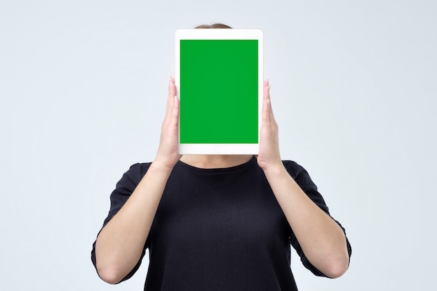 Jeune femme tenant une tablette vierge devant son visage avec copie espace