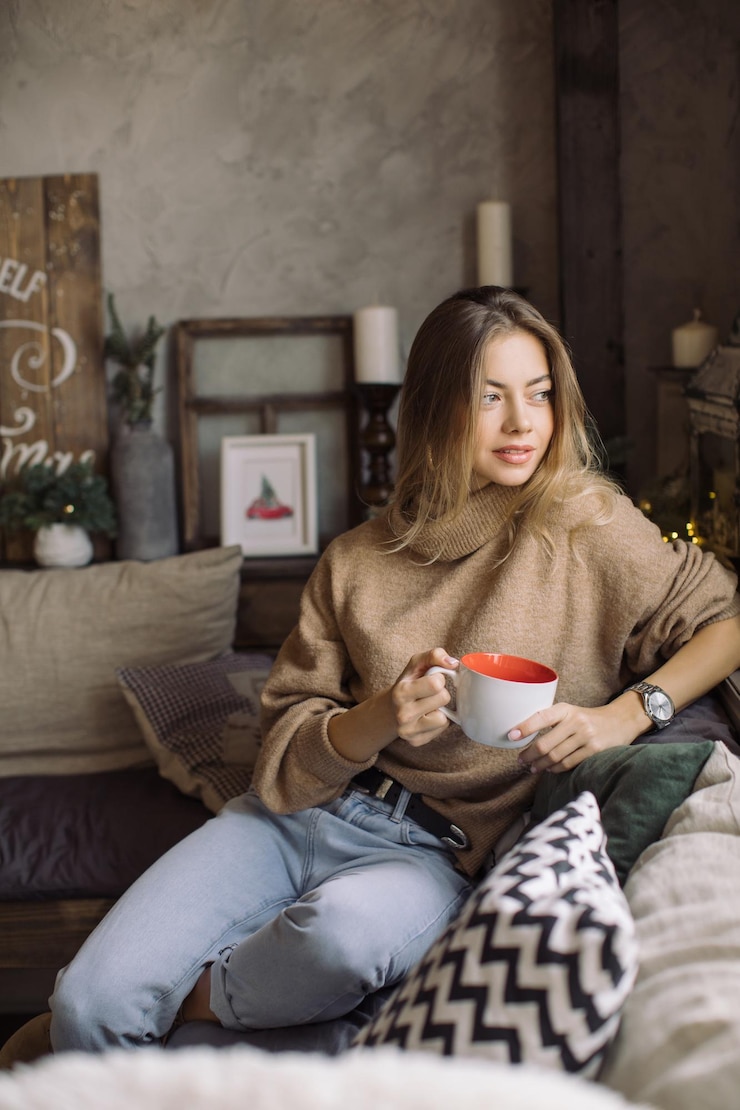 Photo une jeune femme tenant une tasse de café assise sur le canapé à la maison