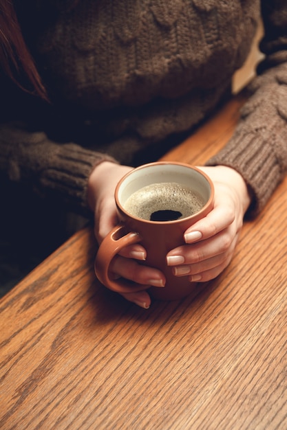 Jeune femme tenant une tasse de café chaud dans ses mains