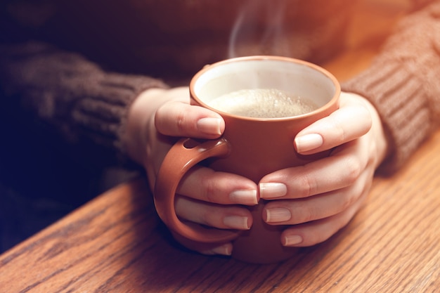 Jeune femme tenant une tasse de café chaud dans ses mains