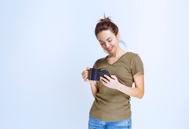 Jeune femme tenant une tasse de café et parlant au téléphone