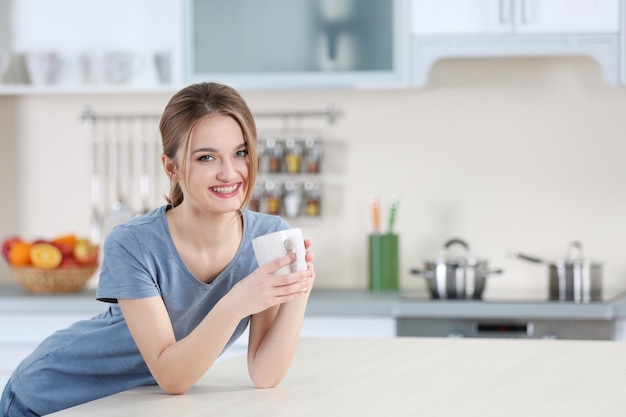 Jeune femme tenant une tasse dans la cuisine