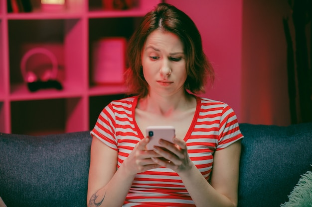 Jeune femme tenant un téléphone intelligent en regardant l'écran du téléphone portable à l'aide d'applications mobiles pour faire du shopping
