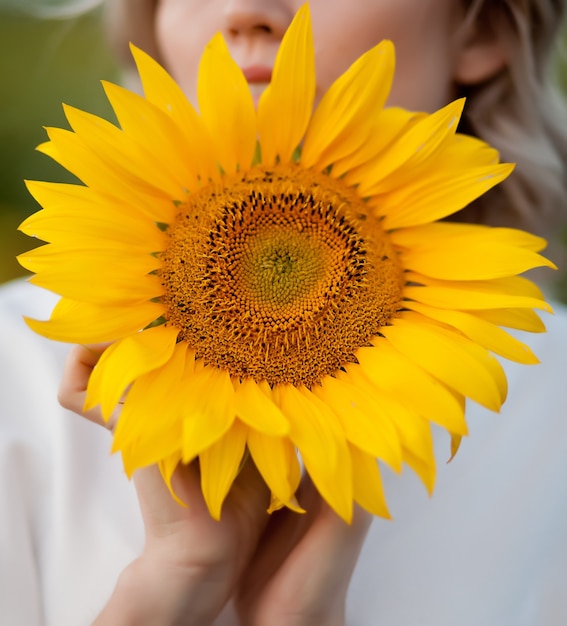 Jeune femme tenant un tournesol dans une main