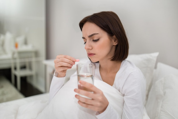 Jeune femme tenant un verre d'eau et une capsule rose