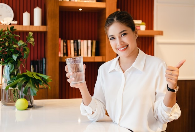 Jeune femme tenant un verre d'eau pure dans la cuisine