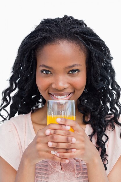 Une jeune femme tenant un verre de jus d&#39;orange avec ses deux mains