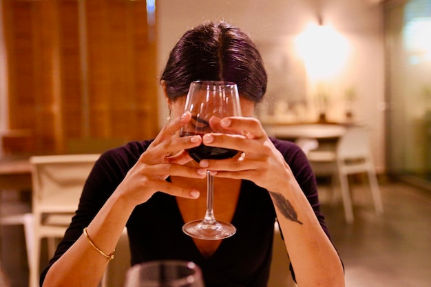 Une jeune femme tenant un verre de vin alors qu'elle est assise dans un restaurant
