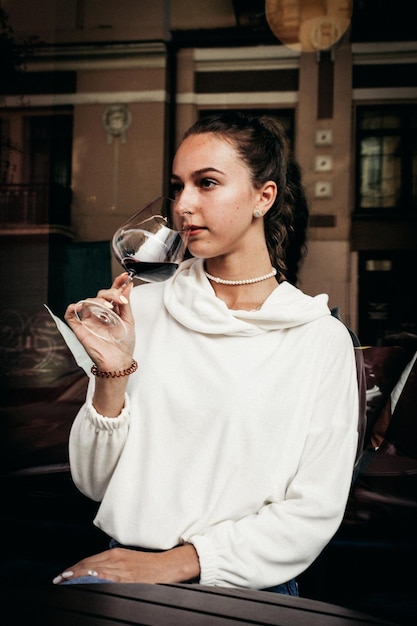 Une jeune femme tenant un verre de vin rouge.