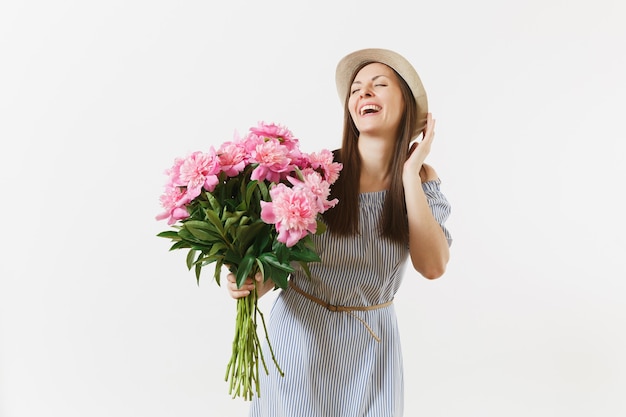 Jeune femme tendre en robe bleue, chapeau tenant un bouquet de belles fleurs de pivoines roses isolées sur fond blanc. Saint-Valentin, concept de vacances de la Journée internationale de la femme. Espace publicitaire.