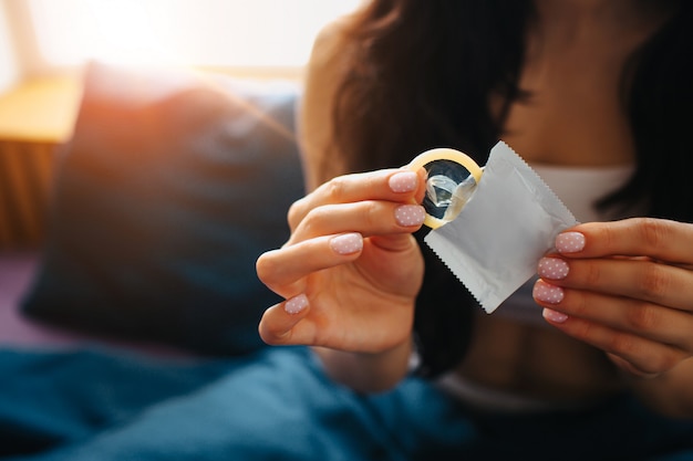 Jeune femme tenir le préservatif à la main. Sécurité sexuelle