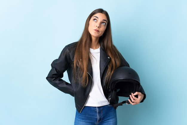 Jeune femme, tenue, a, casque moto, isolé, sur, mur bleu, et, recherche
