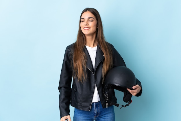 Jeune femme, tenue, a, casque moto, isolé, sur, mur bleu, rire