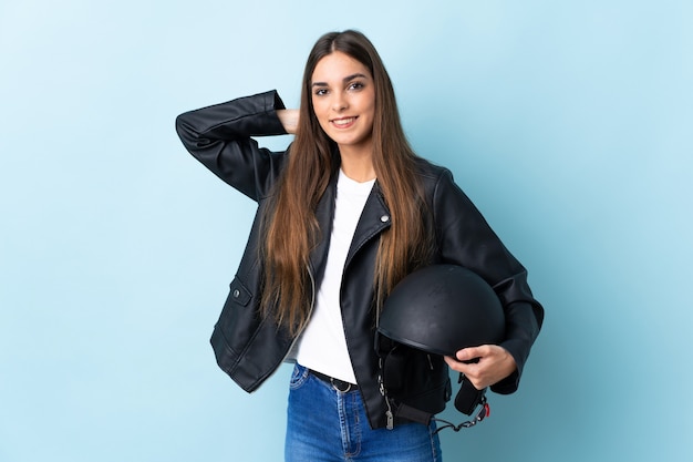 Jeune femme, tenue, a, casque moto, isolé, sur, mur bleu, rire
