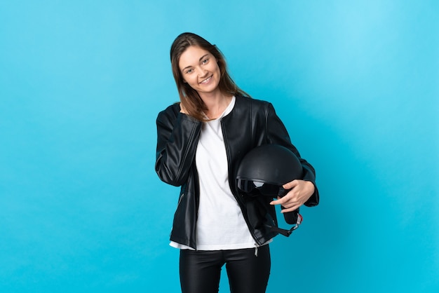 Jeune femme, tenue, a, casque moto, isolé, sur, mur bleu, rire