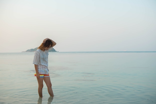 Jeune femme en tenue décontractée et debout sur la plage