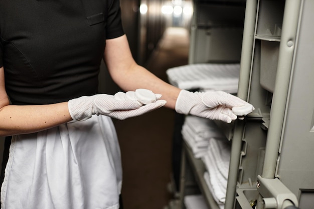 Une jeune femme en tenue élégante organise des draps fraîchement pressés dans un couloir calme.
