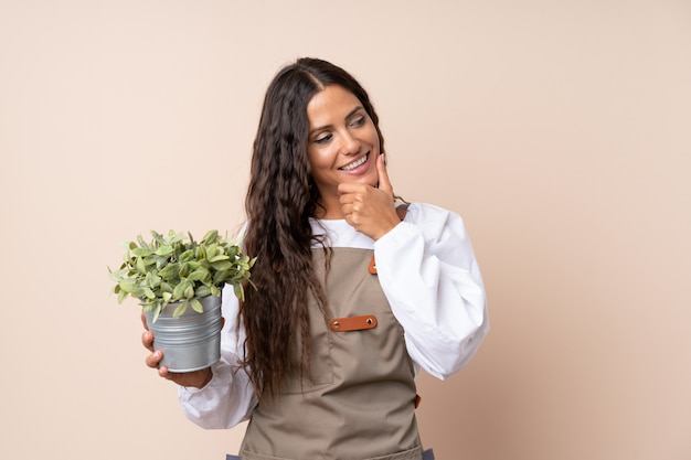 Jeune femme, tenue, plante, penser, idée, côté, regarder