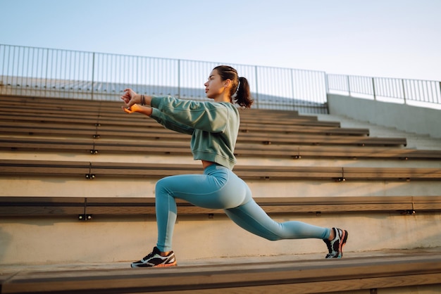 Une jeune femme en tenue de sport faisant des exercices à l'extérieur le matin Une femme faisant des exercises d'étirement