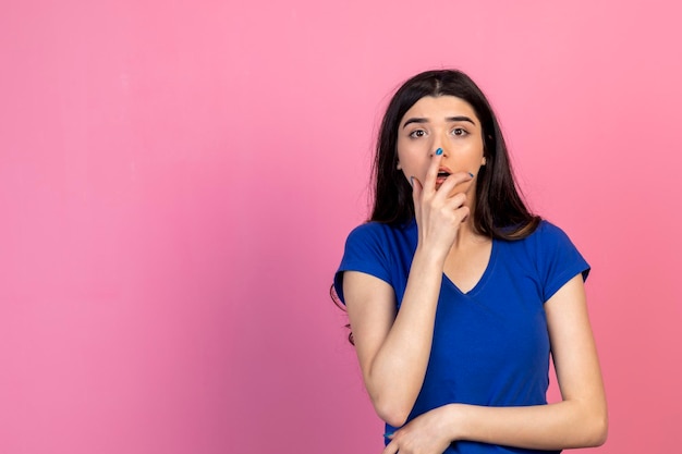 Jeune femme terrifiée tenant sa main à la bouche hr sur fond rose Photo de haute qualité