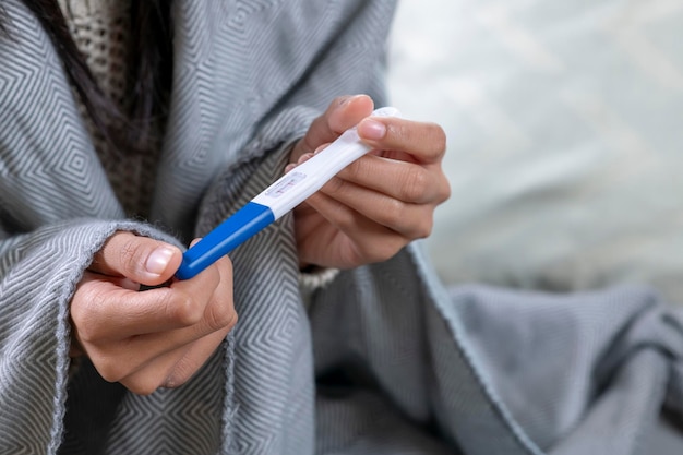 Jeune femme avec test de grossesse dans la chambre libre