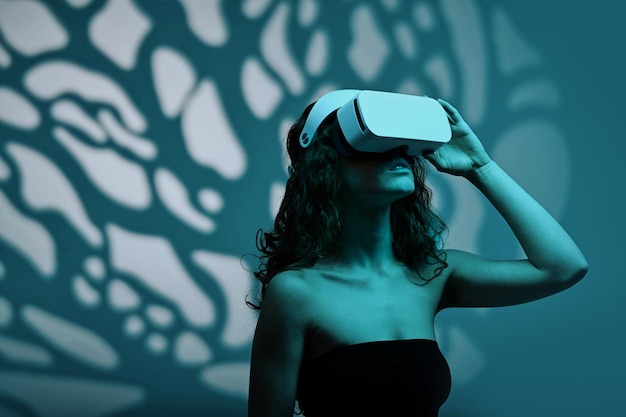 Jeune femme testant des lunettes de réalité virtuelle debout sur le fond de l'ombre du motif